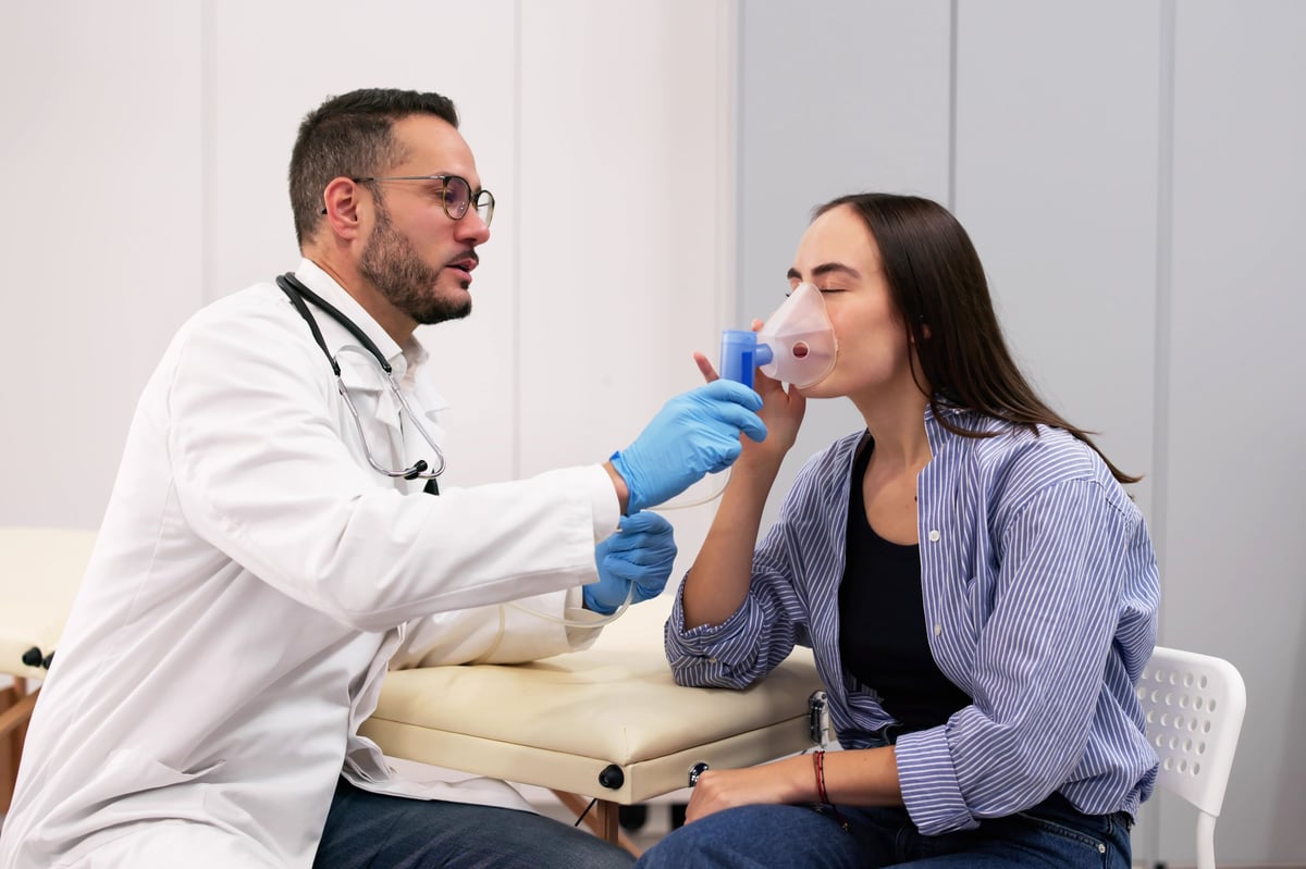 Paciente respiratoria recibiendo tratamiento con nebulizador en clínica pulmonar
