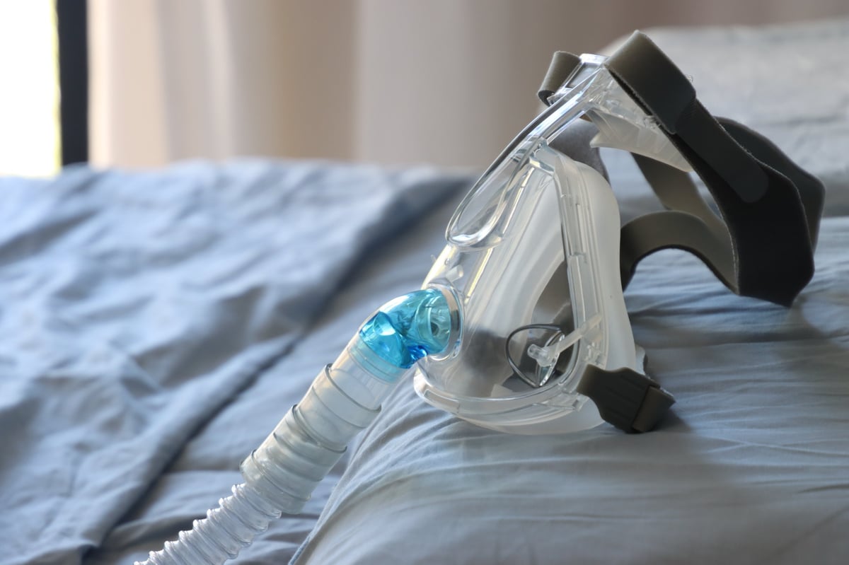 Mascarilla y tubo de tratamiento respiratorio sobre fondo claro