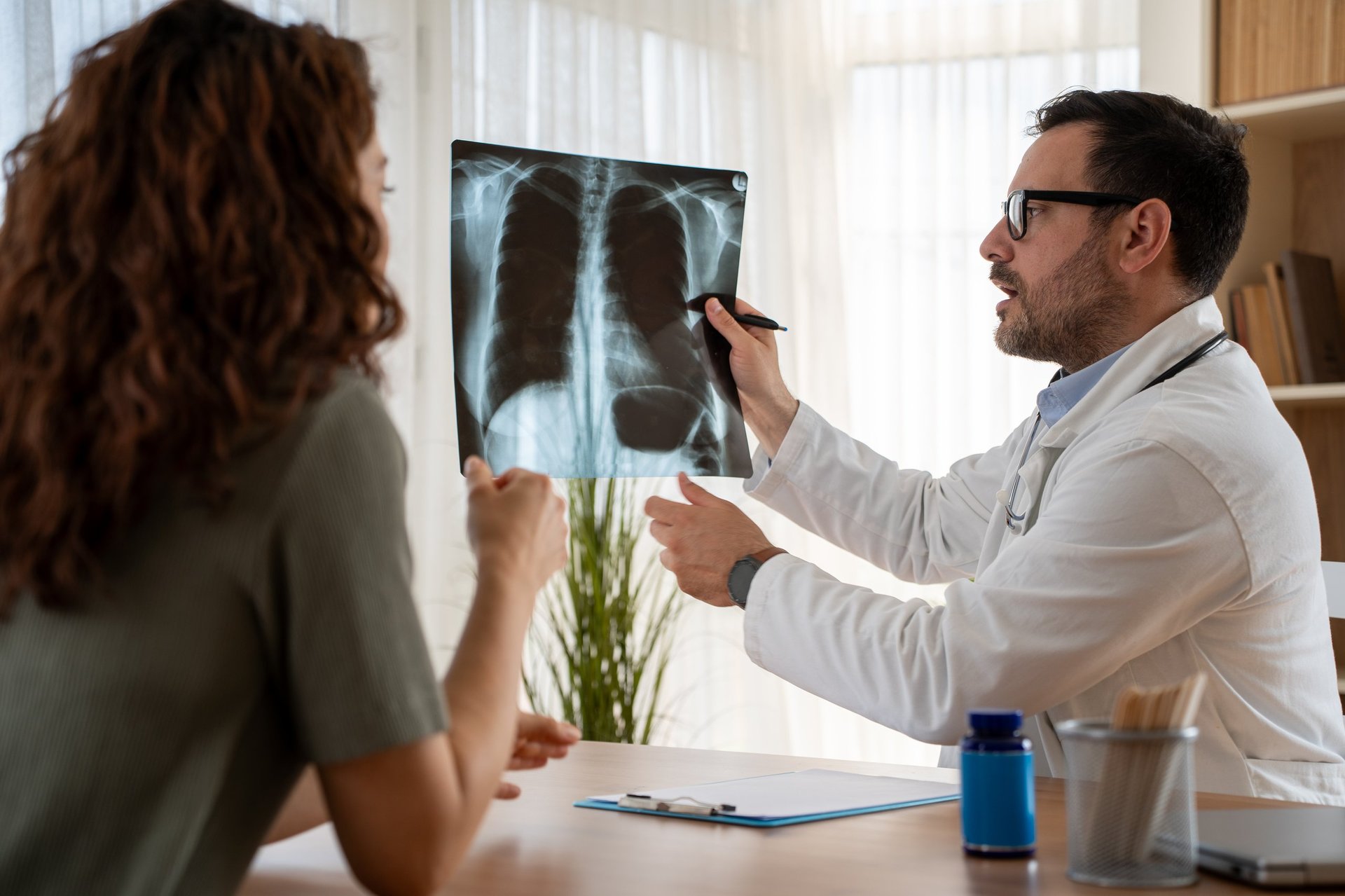 Consulta médica en la que el médico explica los resultados de una radiografía de tórax al paciente.