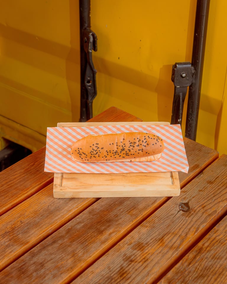 Seeded baguette on striped paper displayed on wooden stand against yellow background