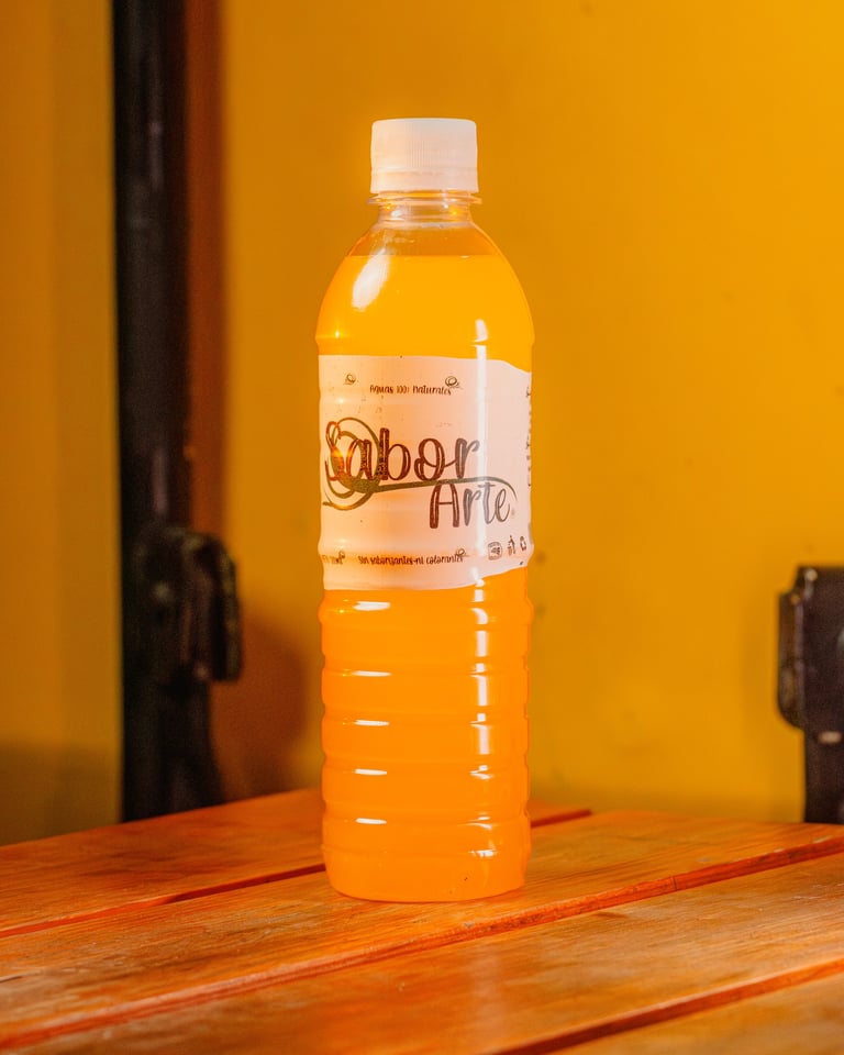 Plastic bottle of orange juice labeled Sabor Artic on wooden table against yellow background